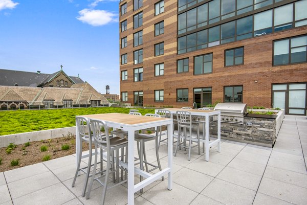 Outdoor grill area and patio with modern seating at Harvest Apartments, ideal for gatherings and relaxation