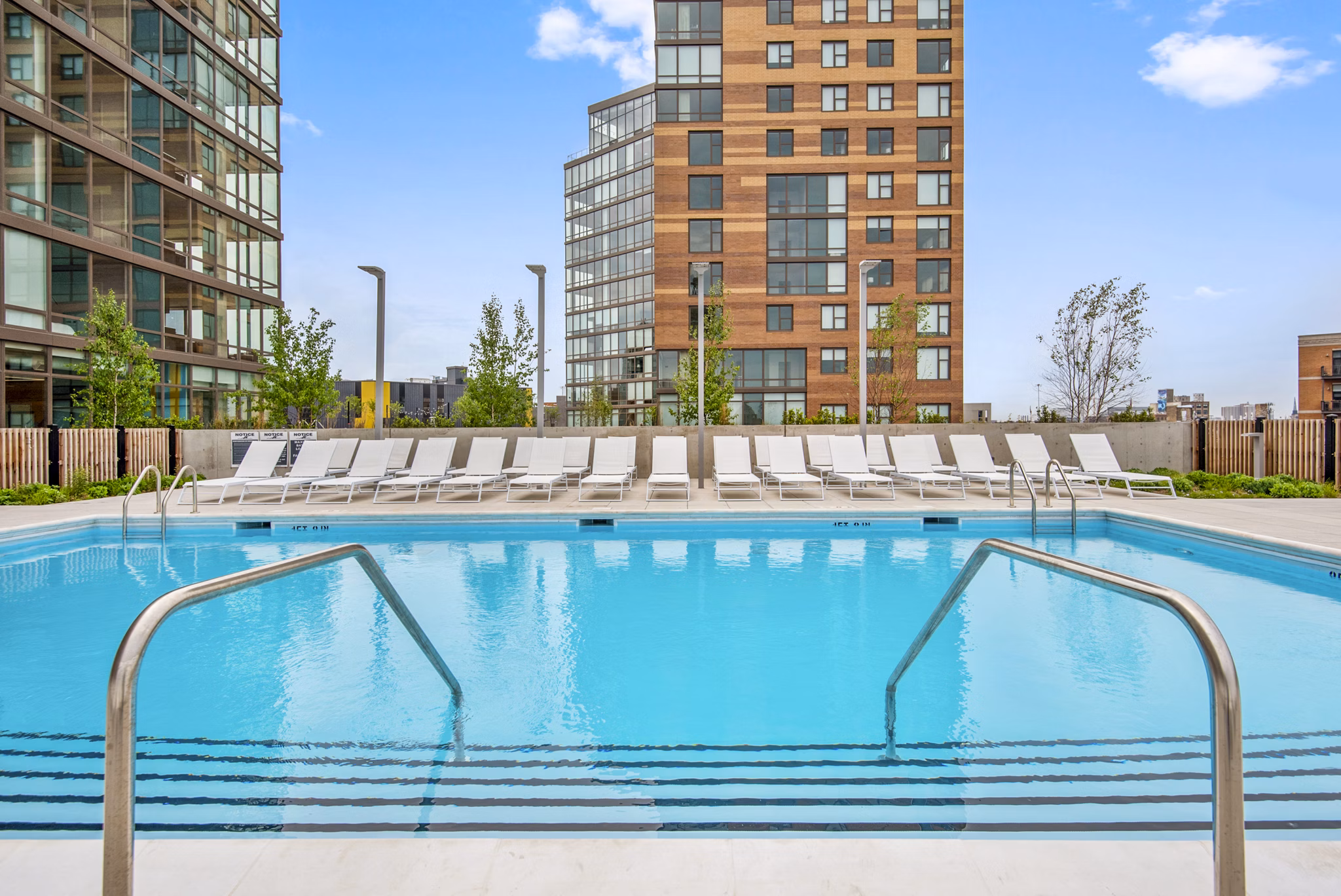 Modern outdoor pool with lounge chairs at Spoke Apartments, perfect for relaxation and leisure in luxury living environment