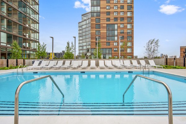 Modern outdoor pool with lounge chairs at Spoke Apartments, perfect for relaxation and leisure in luxury living environment