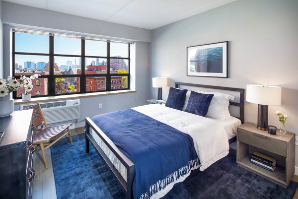 Cozy bedroom with modern decor and ample natural light at Embankment House Apartments in a luxury Greystar community