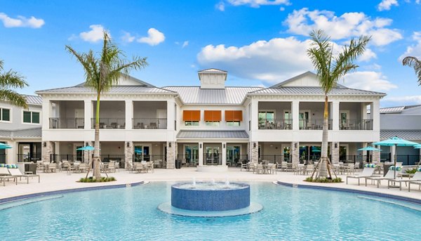 Resort-style pool at Encore at Tradition Apartments with luxurious poolside seating and tropical landscaping