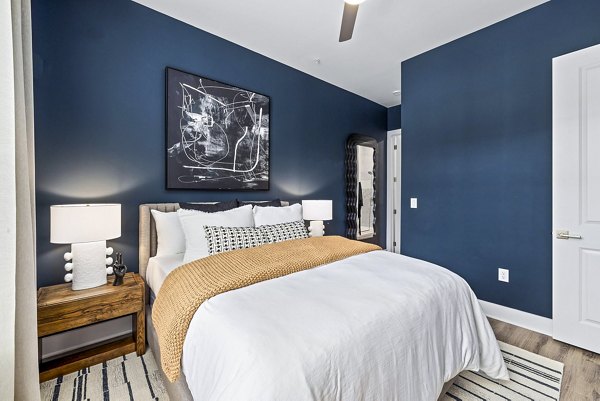 Bedroom featuring modern decor and large windows at The Keaton at Brier Creek Apartments