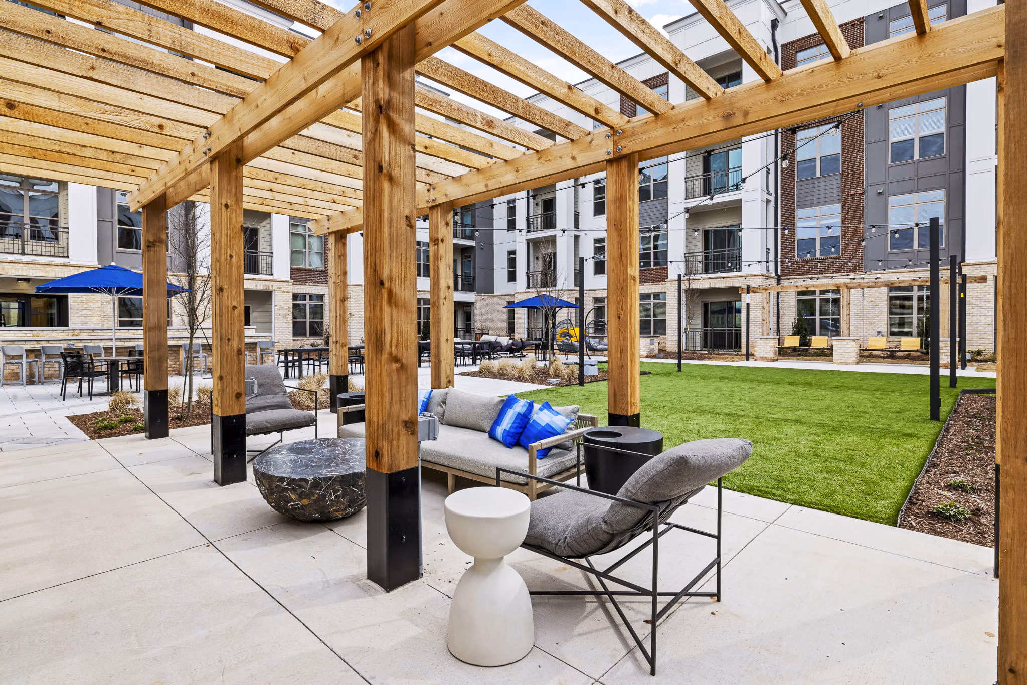 The Keaton at Brier Creek Apartments: Modern patio with outdoor seating and lush landscaping in luxury setting