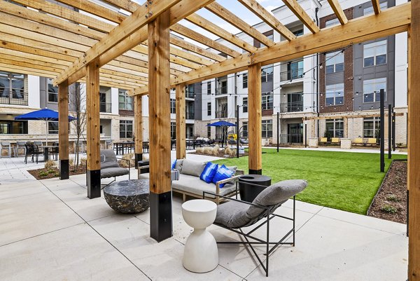 The Keaton at Brier Creek Apartments: Modern patio with outdoor seating and lush landscaping in luxury setting