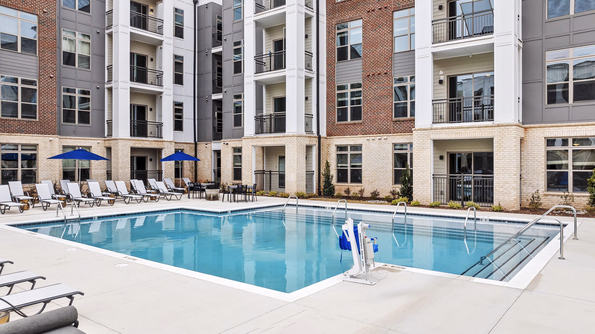 Resort-style pool with sun loungers at the Keaton at Brier Creek Apartments, offering luxury leisure in a scenic setting
