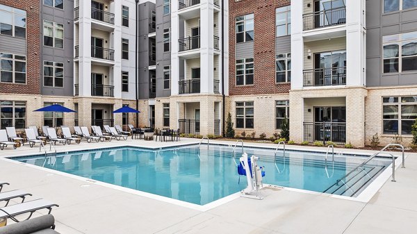 Resort-style pool with sun loungers at the Keaton at Brier Creek Apartments, offering luxury leisure in a scenic setting