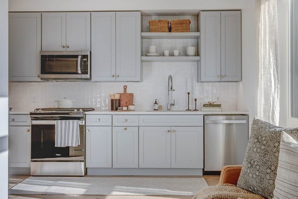 Modern kitchen with stainless steel appliances and quartz countertops in Camber Apartments