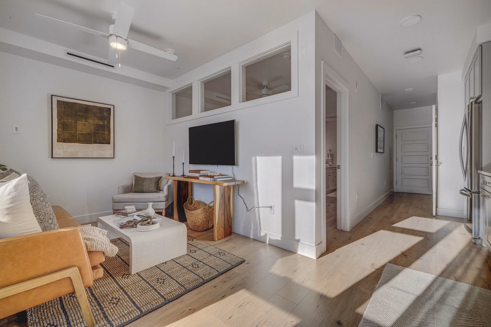 Spacious living room featuring modern decor and large windows in Camber Apartments