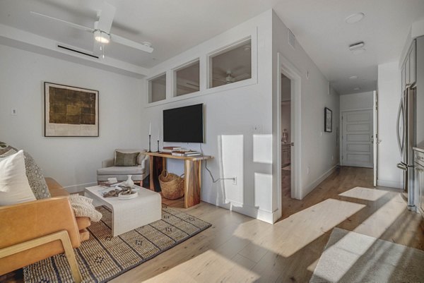 Spacious living room featuring modern decor and large windows in Camber Apartments