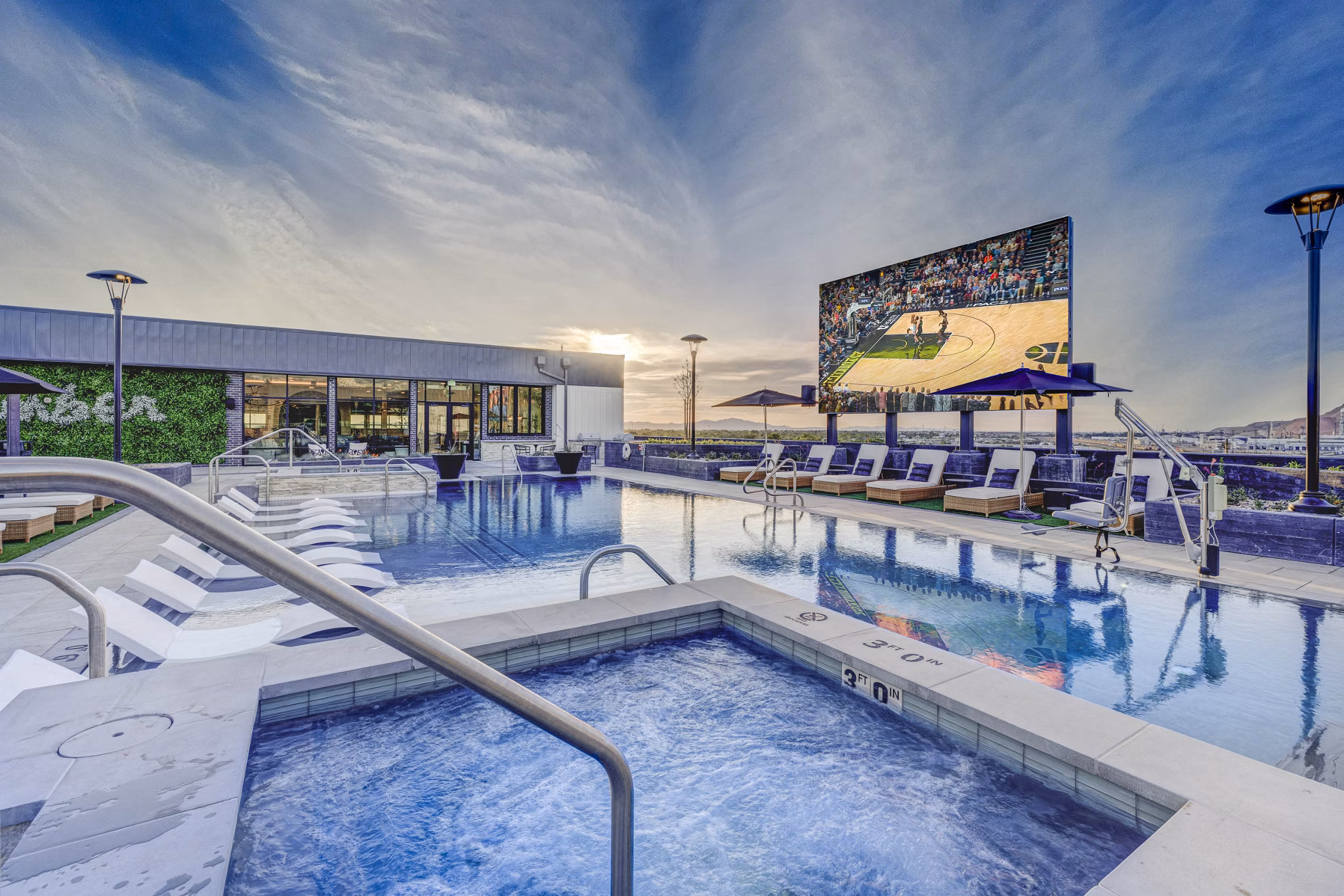 Relax by the sparkling pool at Camber Apartments with sun loungers and lush landscaping, a perfect retreat for residents
