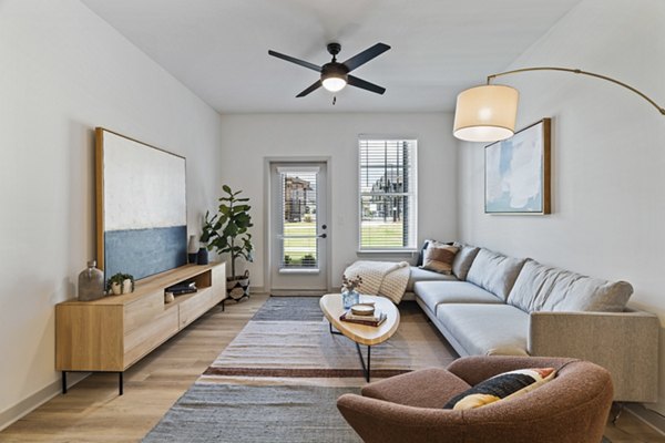 Living room with modern furnishings and large windows at The Gabriel Apartments, a Greystar luxury property