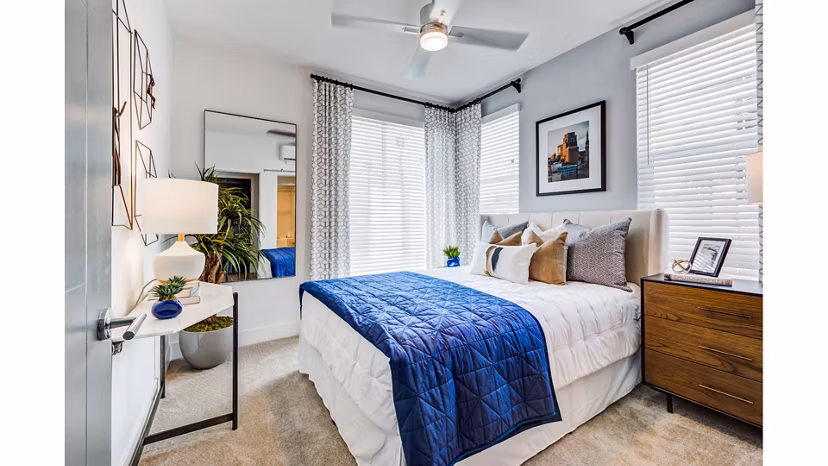 Modern bedroom with stylish decor at The Eisley Apartments, featuring large windows and sleek furnishings for a luxurious living experience