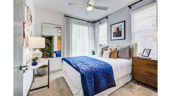 Modern bedroom with stylish decor at The Eisley Apartments, featuring large windows and sleek furnishings for a luxurious living experience