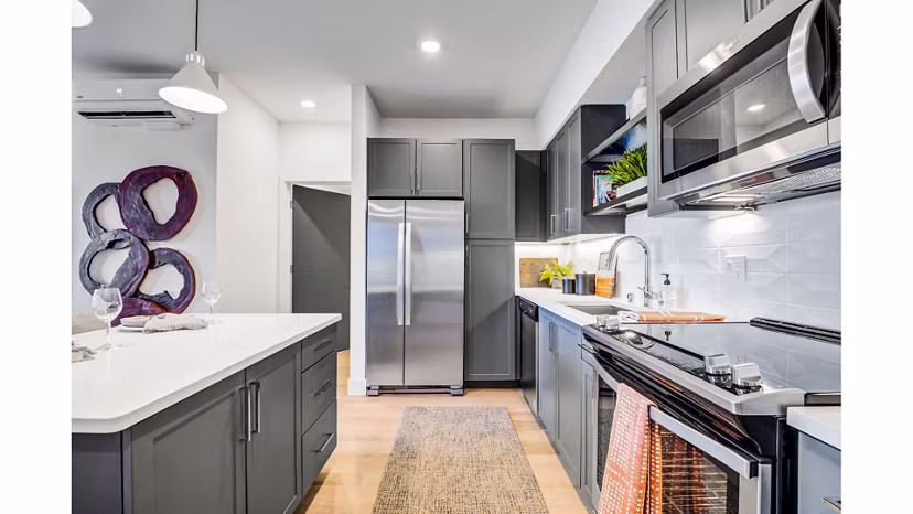 Modern kitchen featuring stainless steel appliances and marble countertops in The Eisley Apartments