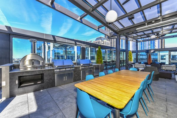 Outdoor grill area and patio at Novel Midtown Apartments featuring modern seating and lush greenery