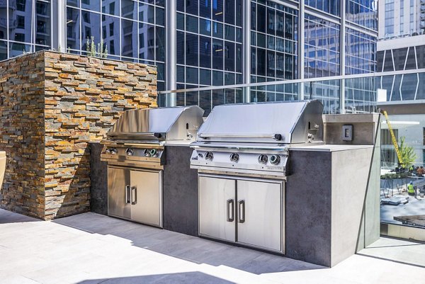 Grill area with modern patio furniture at Novel Midtown Apartments for outdoor gatherings