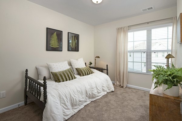 Cozy bedroom with natural light at Townes at Hamilton Apartments, featuring modern decor and ample storage spaces