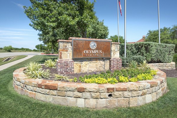 Signage displaying the entrance to Olympus Team Ranch Apartments, luxury living spaces with modern amenities