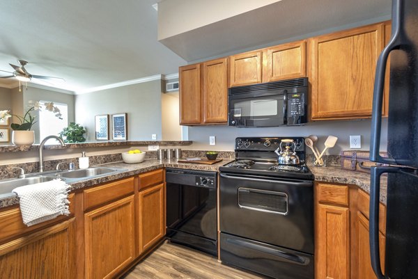 Modern kitchen with stainless steel appliances and white cabinetry at Olympus Team Ranch Apartments