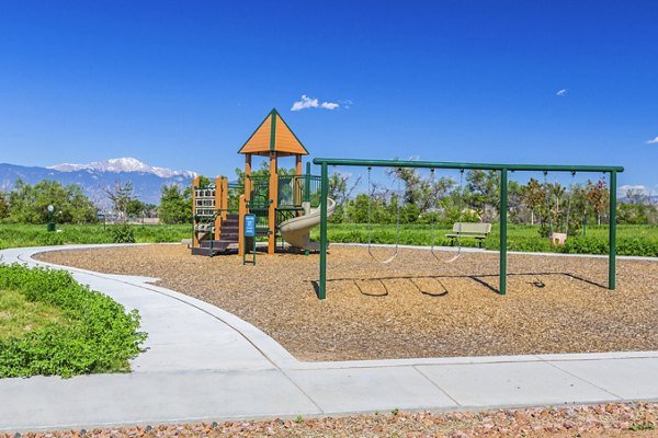 Children's playground with slides and climbing structures at Retreat at Patriot Park Apartments in a lush outdoor setting