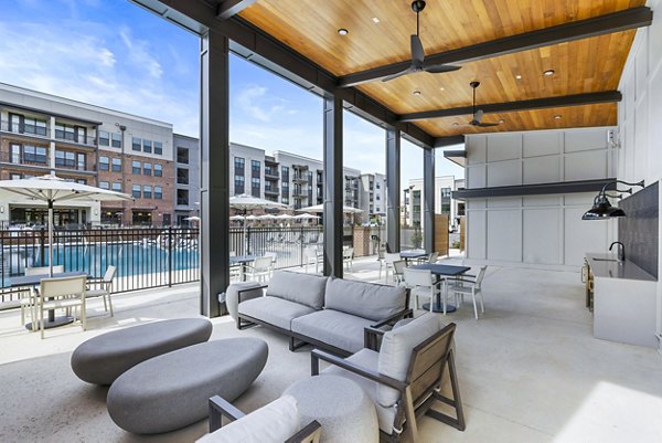 Outdoor grill area and patio at The Premier Apartments with lush landscaping