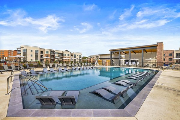 Resort-style pool at The Premier Apartments offers luxury relaxation with sun loungers and palm trees