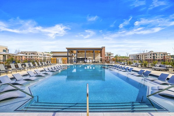 Outdoor pool with comfy lounge chairs at The Premier Apartments, offering luxury relaxation in a serene environment
