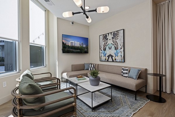 Clubhouse at Mira Raleigh Apartments: Modern lounge area with cozy seating and large windows, ideal for gatherings in Greystar's luxury community
