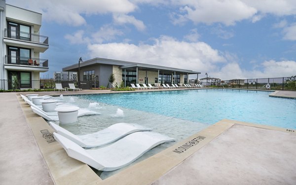 Pool with sun loungers and palm trees at The Sommery Apartments