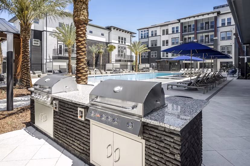 Grill area and pool patio at The Elliott Apartments featuring modern outdoor seating and greenery