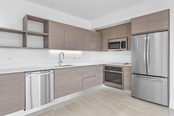 Modern kitchen with quartz countertops and stainless steel appliances at The Vibe Miami Apartments