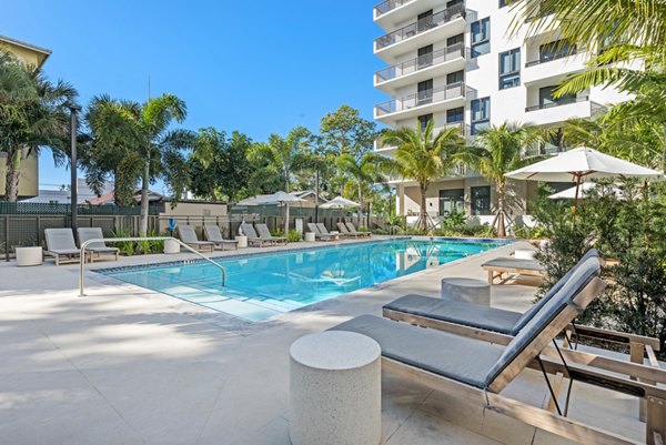 Relaxing outdoor pool at The Vibe Miami Apartments with lounge chairs and lush palms