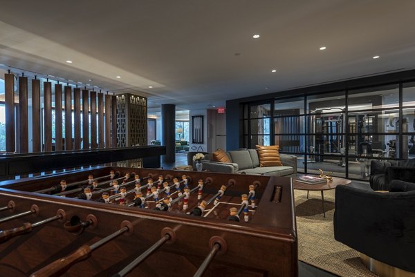 Entertainment lounge with foosball table and seating area overlooking the fitness center