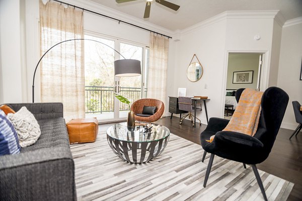 Bright living room with modern decor in Bayou on the Bend Apartments, featuring large windows and comfortable seating