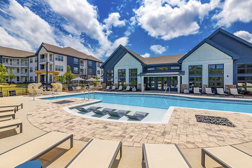 Expansive outdoor pool at Marlowe South Fulton Apartments with modern lounge furniture and surrounding greenery