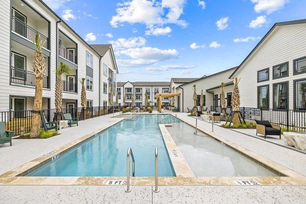 Resort-style pool with lounge chairs at Asher Apartments, offering luxury outdoor amenities for relaxation and leisure