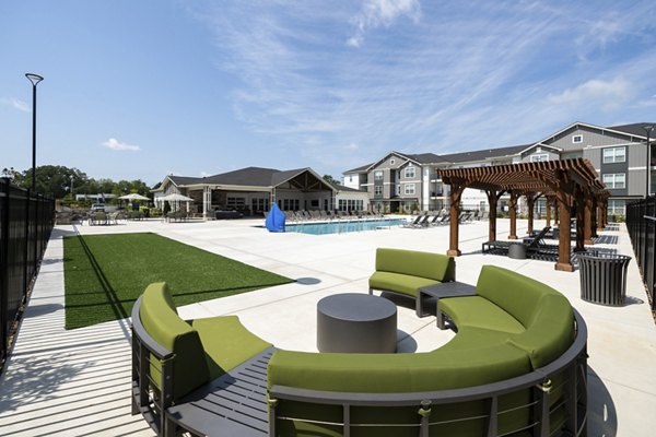 Patio area with cozy seating and lush greenery at The Mill at White House Apartments, offering serene outdoor leisure space for residents