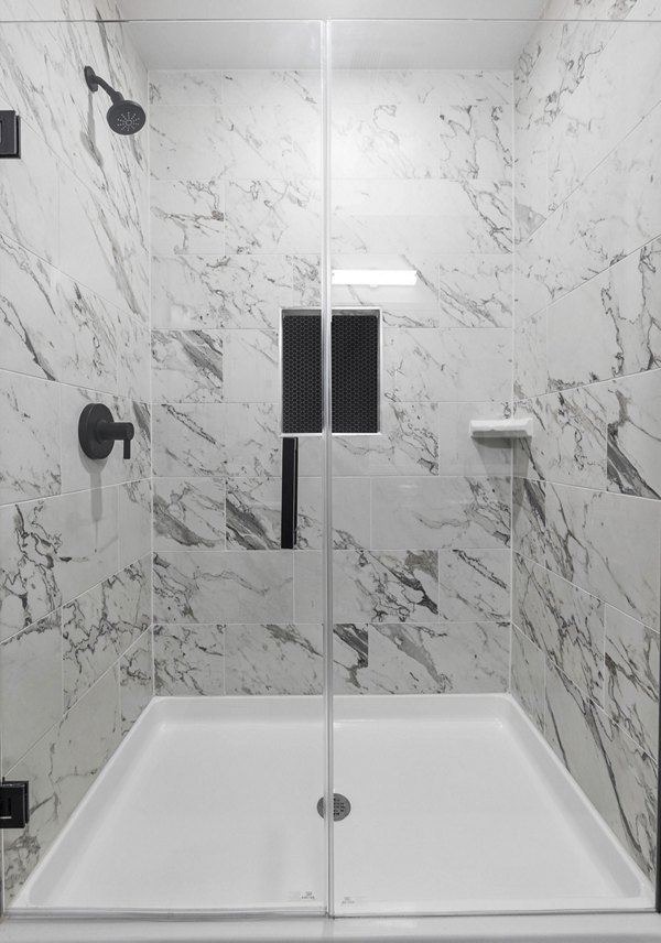 Modern bathroom with sleek design at The MAV Apartments featuring ceramic tiles and glass shower