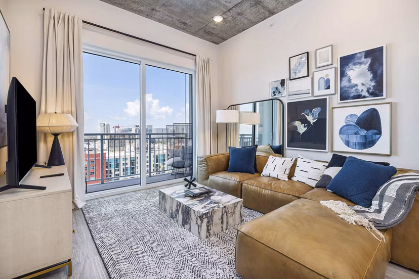 Modern living room with sleek furniture and large window in The MAV Apartments