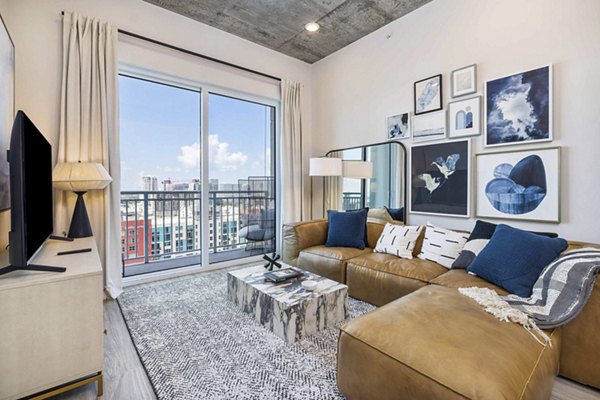 Modern living room with sleek furniture and large window in The MAV Apartments
