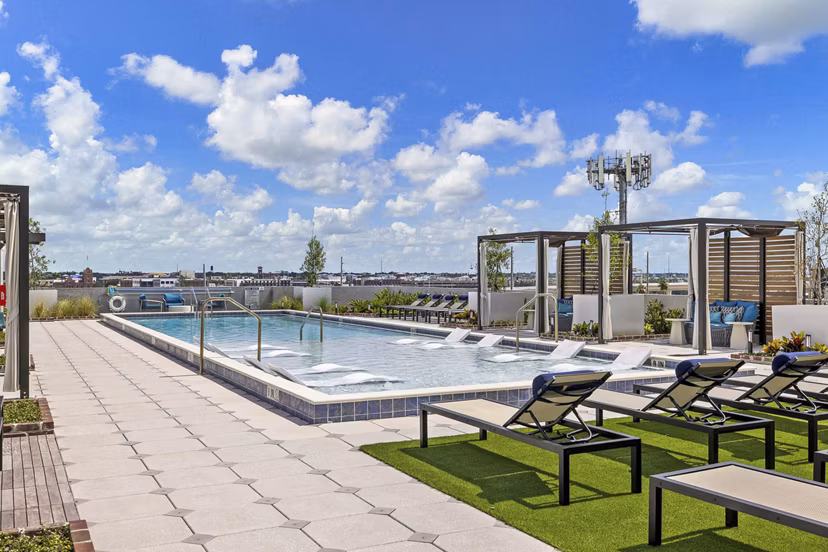 Modern outdoor pool with sun loungers at The MAV Apartments providing luxury relaxation in Greystar community