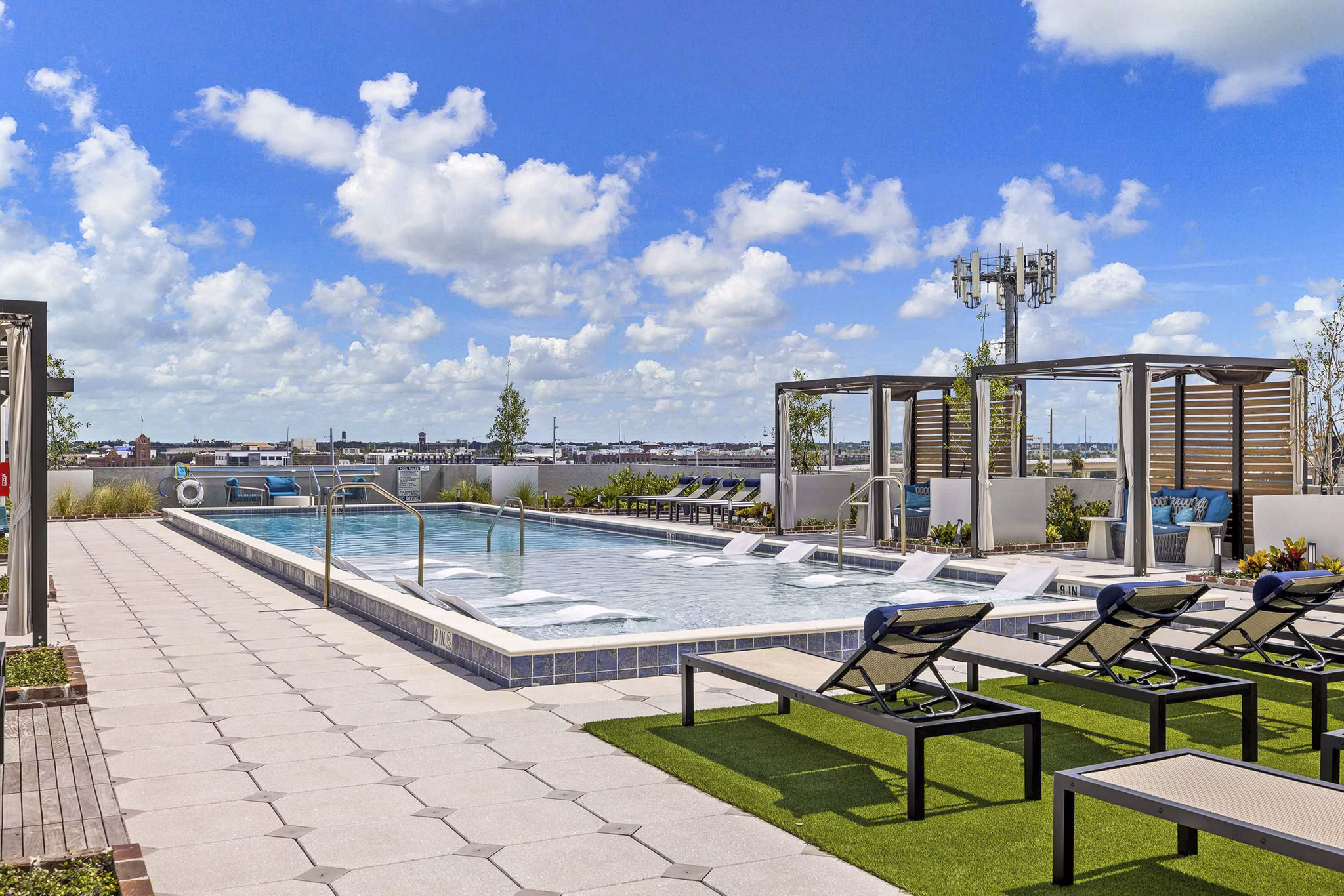 Modern outdoor pool with sun loungers at The MAV Apartments providing luxury relaxation in Greystar community