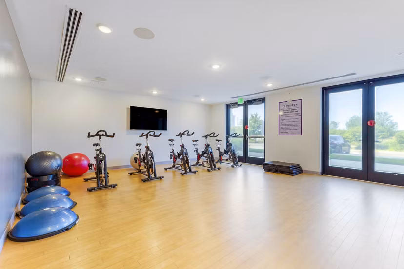 Yoga and spin studio with mirrored walls and exercise bikes at Tapestry Largo Station Apartments