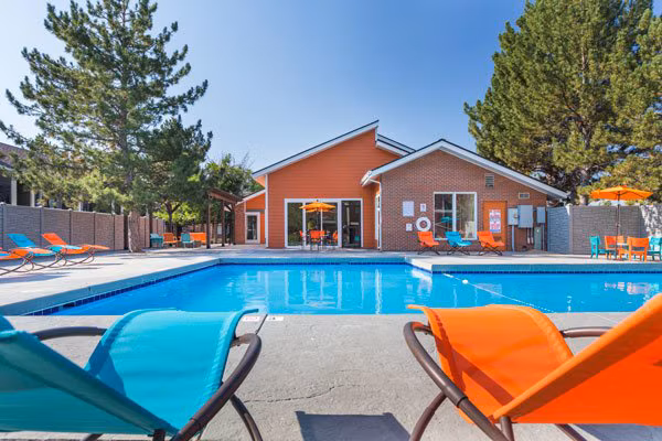 Pool area with lounge chairs and umbrellas at Retreat at Fitzsimons Apartments offering leisure and relaxation for residents