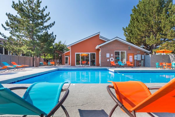 Pool area with lounge chairs and umbrellas at Retreat at Fitzsimons Apartments offering leisure and relaxation for residents