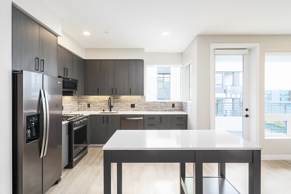 Sleek kitchen with stainless steel appliances and island in Sofia Apartments