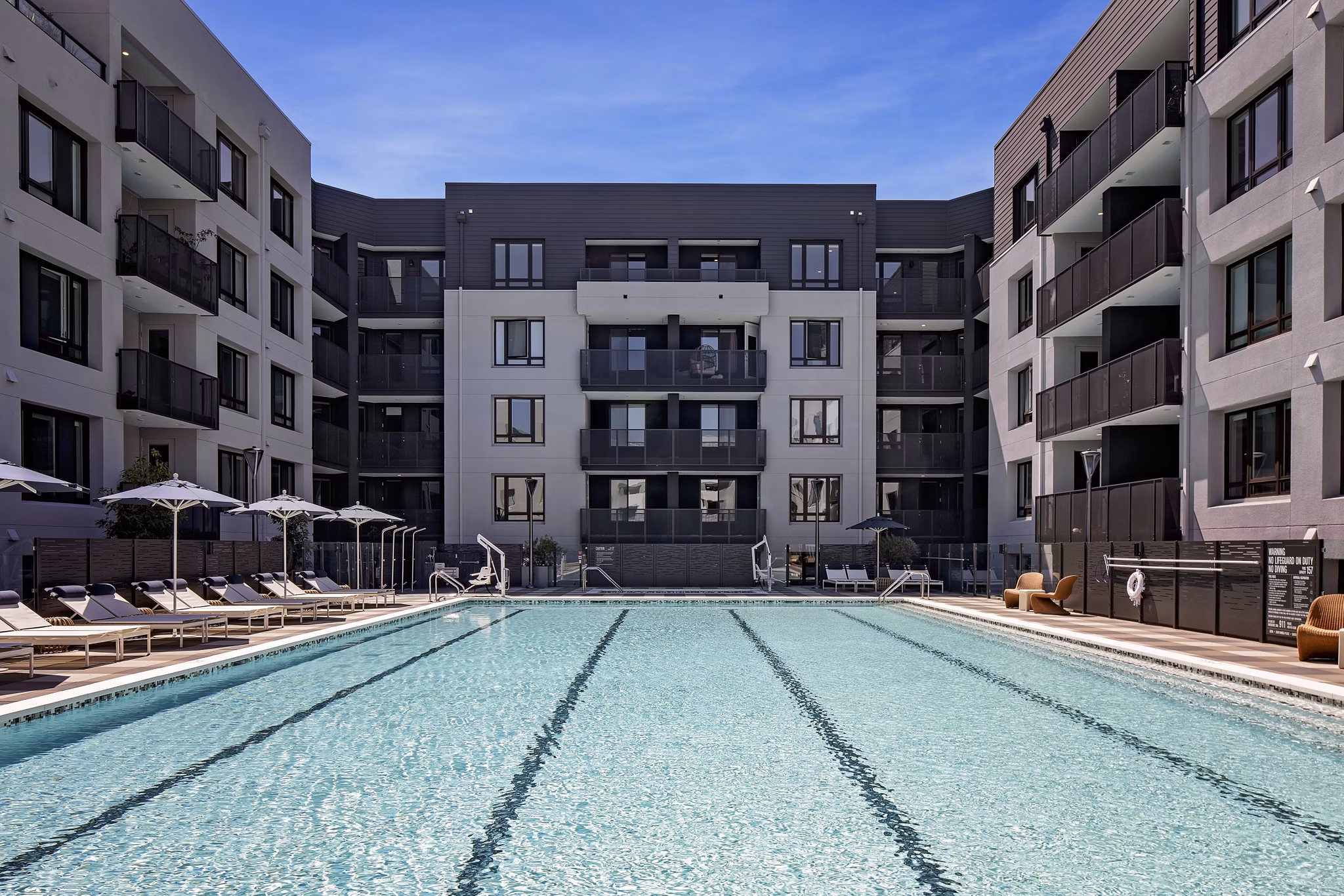 Chic pool area at Sofia Apartments featuring comfortable lounge chairs and lush landscaping
