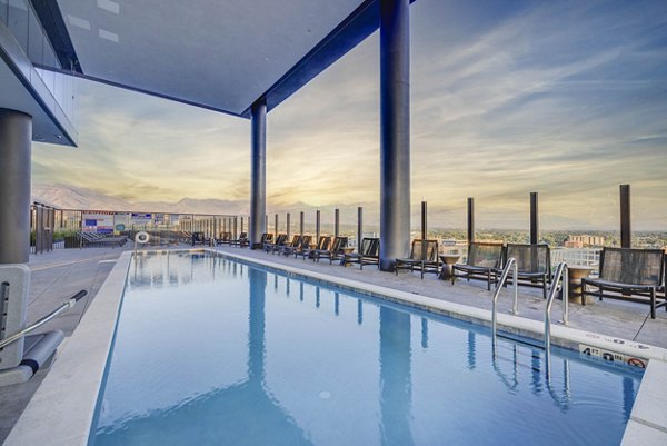 Infinity-edge pool at The Worthington Apartments with surrounding garden area and lounge chairs, ideal for relaxation in a luxury setting