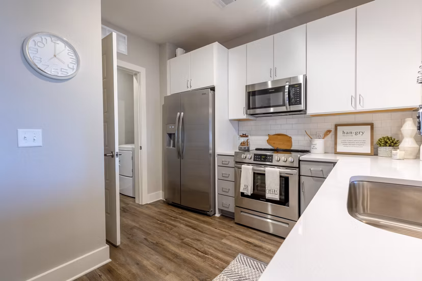 Modern kitchen with stainless steel appliances and island at Newbrook Point Hope Apartments, luxury living by Greystar