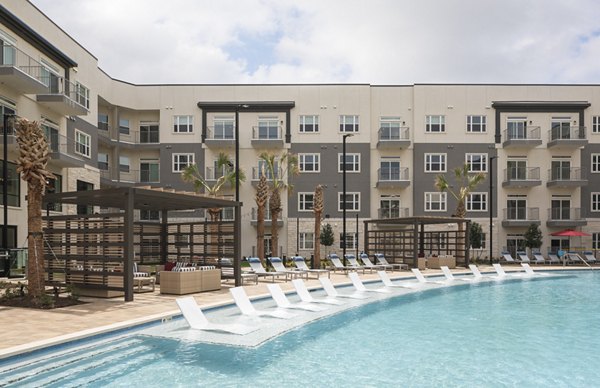 Resort-style pool at Broadstone Frontera Ridge Apartments with palm trees and lounge chairs, ideal for relaxation and social gatherings